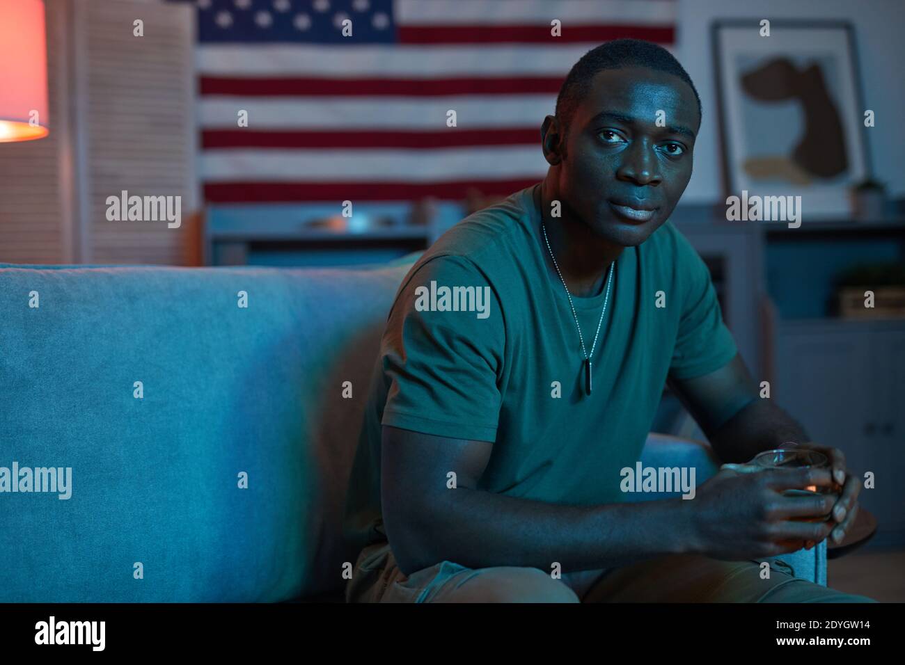 Portrait of African soldier sitting on sofa and drinking alcohol during his retirement Stock Photo