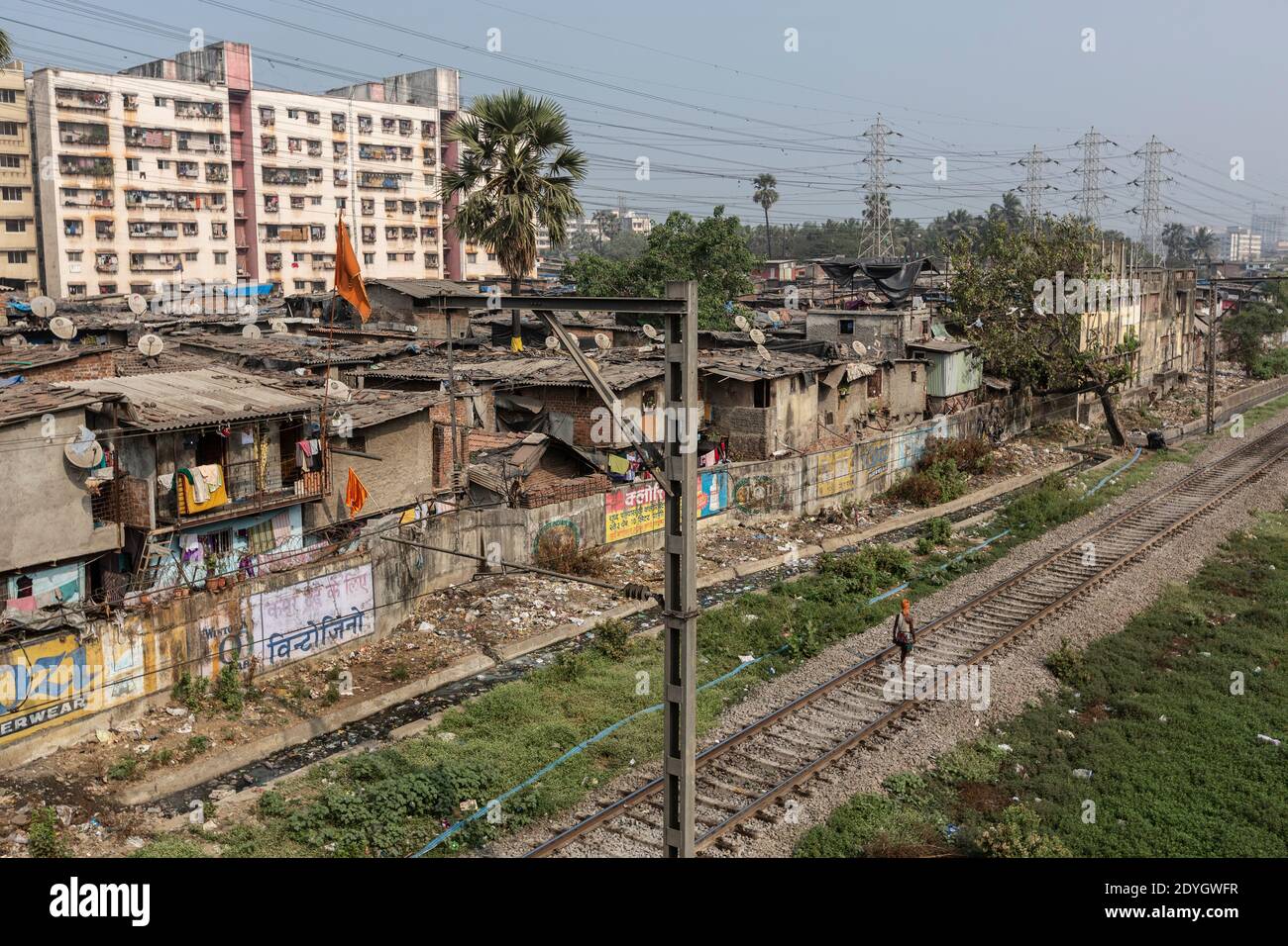Mumbai India Man Walking on train tracks next to Dharavi Slum Stock Photo