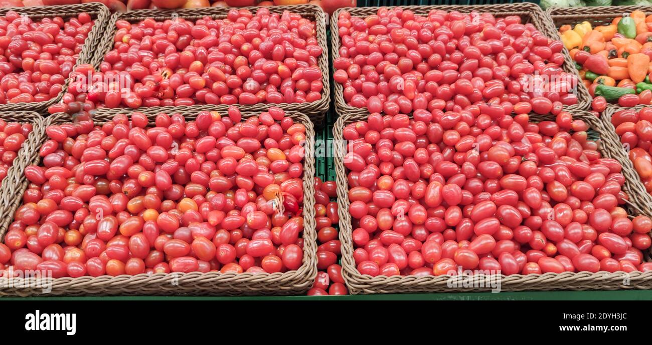 Cherry tomatoes (Solanum lycopersicum var. Cerasiforme) in wooden baskets for sale in a supermarket. Tomatoes whose size is smaller and sweeter. Used Stock Photo