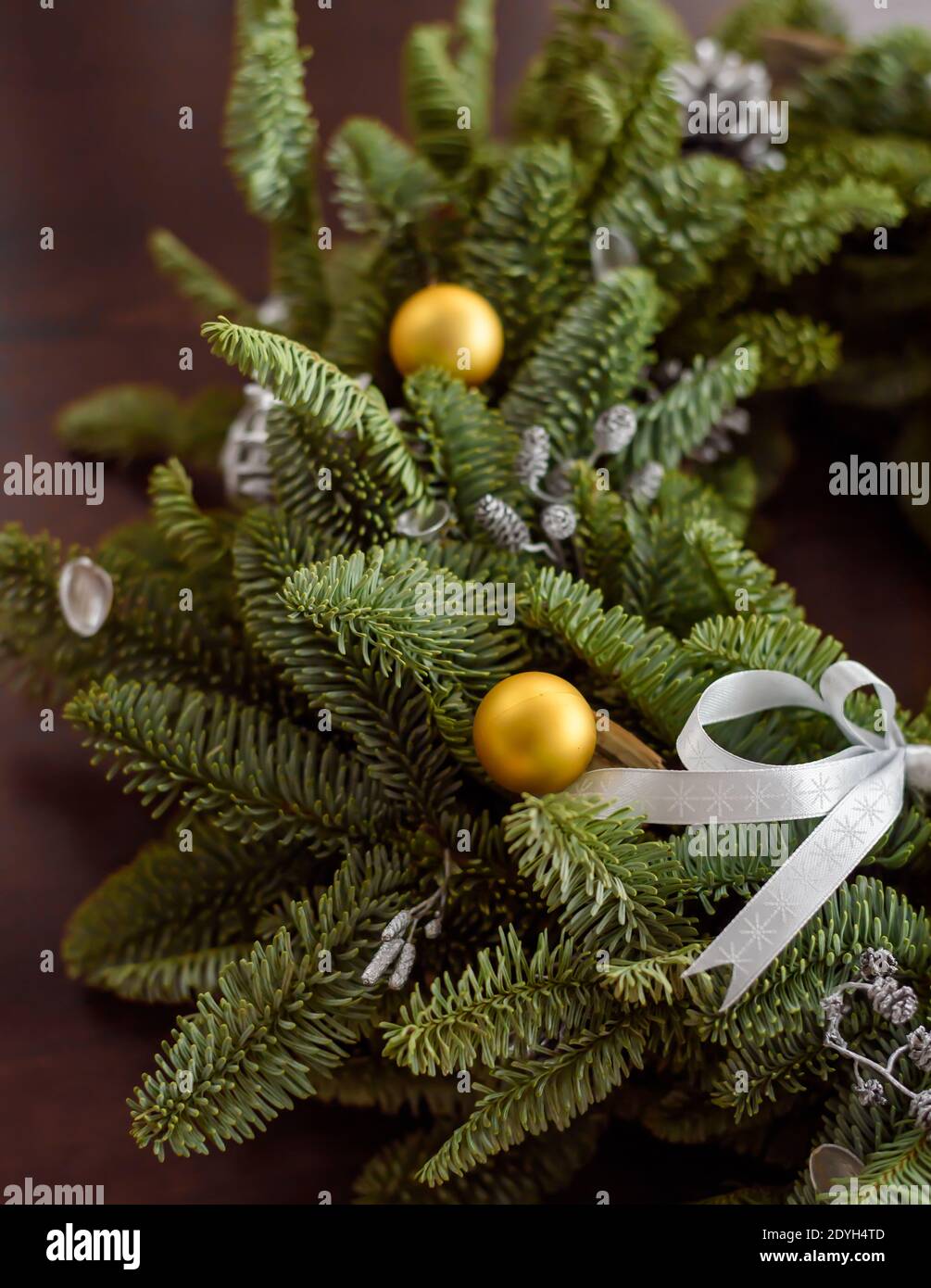 Beauriful green Christmas wreath with golden baubles on a dark wooden surface, 45 degree angle, rich colors Stock Photo