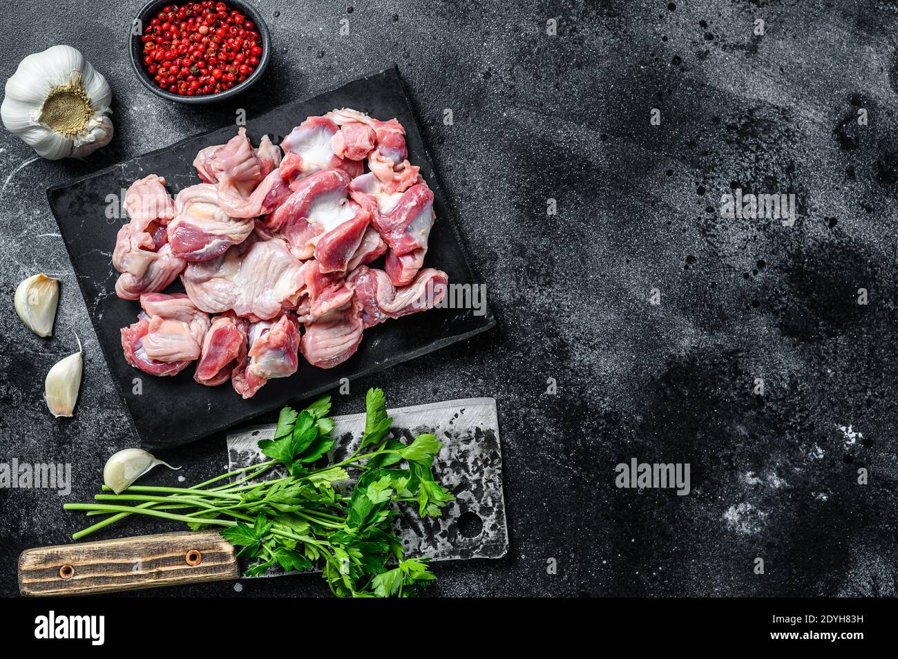 Raw uncooked Bird chicken giblets gizzards, stomachs. Black background