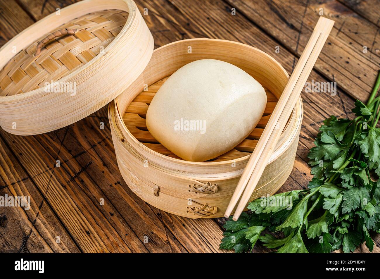 Chinese Steamed Buns in traditional bamboo steamer. Wooden background