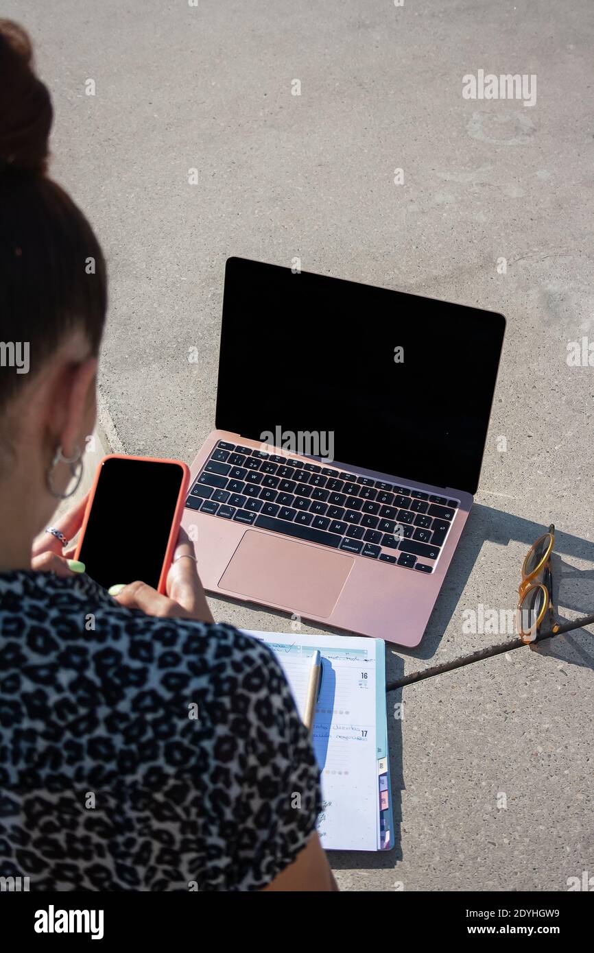 Young woman remote working outside location and typing at her mobile backside view Stock Photo