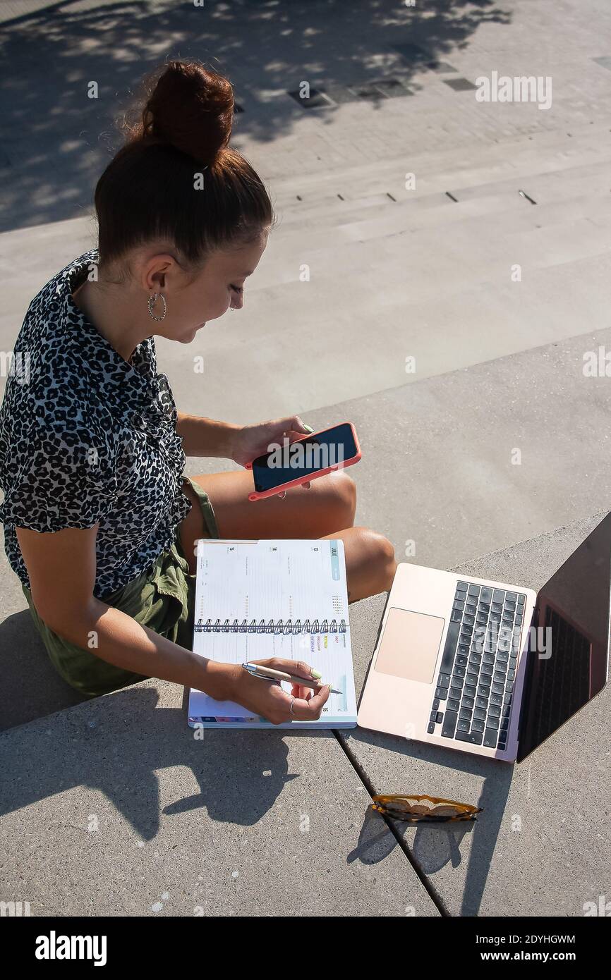 Young woman remote working outside location checking notes Stock Photo