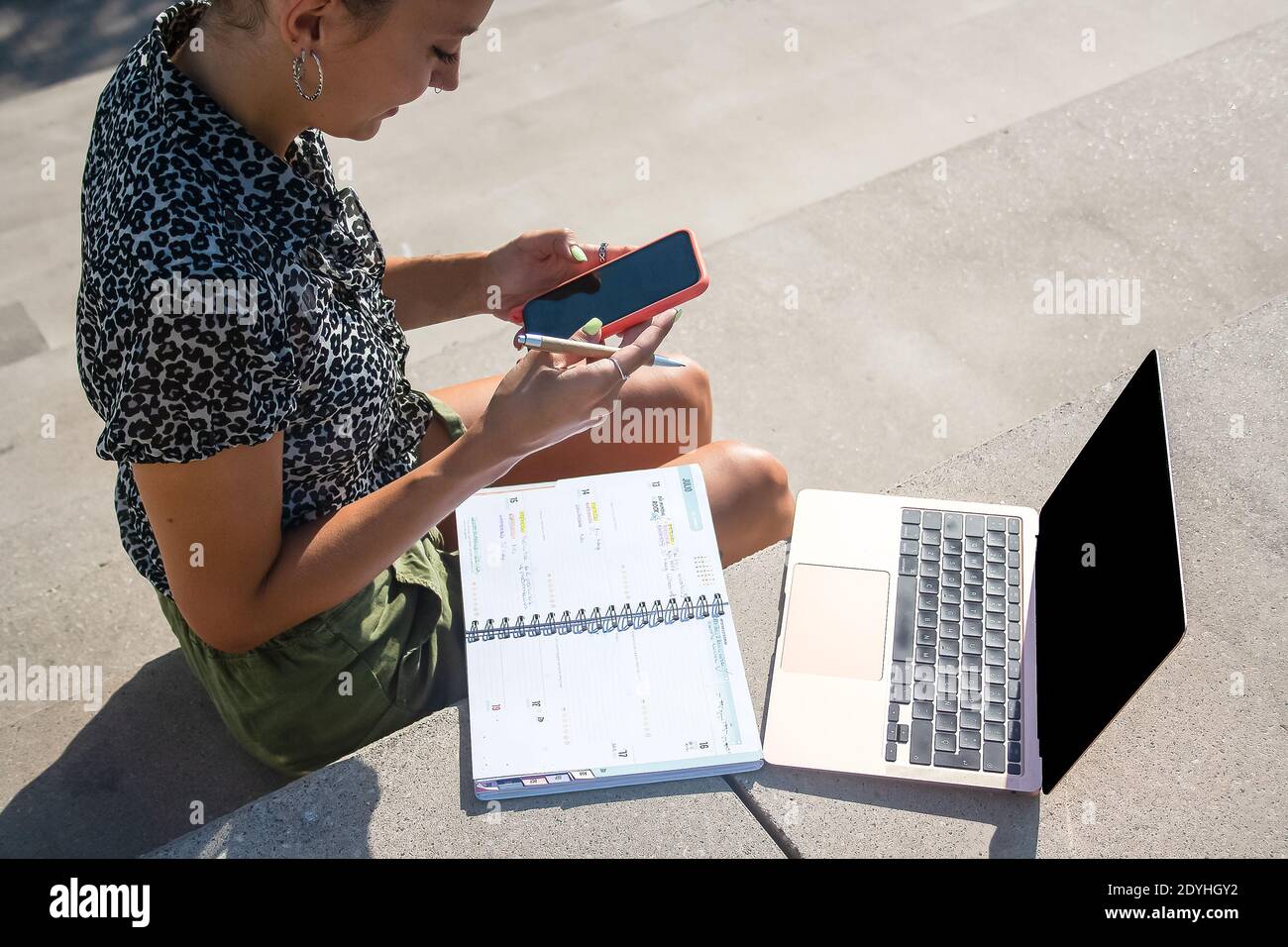 Young woman remote working outside location. Textiing on her mobile Stock Photo