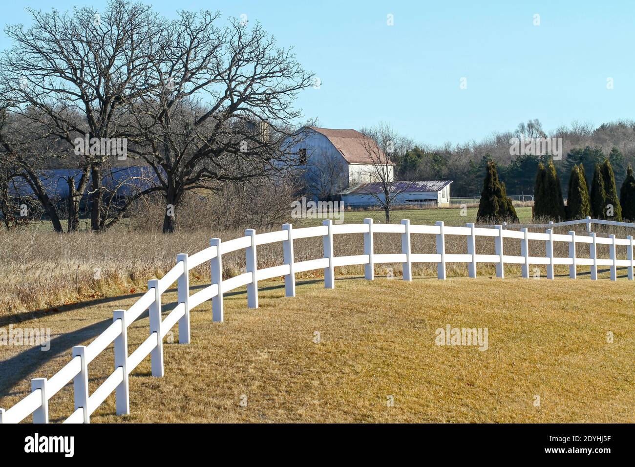 A snowless winter farm scene in rural Wisconsin with white picket fence and barn. Stock Photo