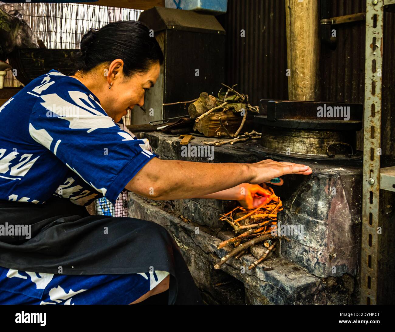 Traditional Japanes Rice Cooking over open Fire by Atsuko Kato. Atsuko Kato in front of her wood-burning stove. The rice for the kaiseki menu is cooked over a wood fire. Locally grown rice, served in handmade ceramic bowls. Stock Photo