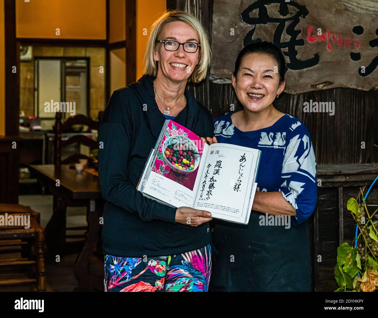 Renowned Japanese chef Atsuko Kato in front of her restaurant Rakan on the Izu Peninsula, Shizuoka, with travel journalist Angela Berg. Calligraphy by Atsuko Kato Stock Photo