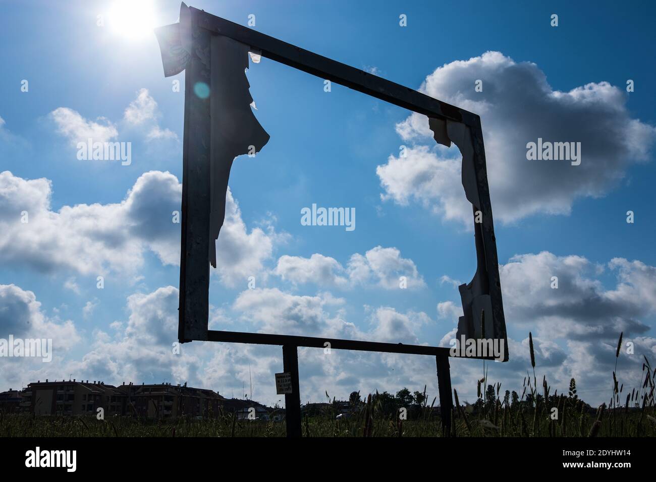 Rusty abandoned advertising outdoor frame with blue sky with clouds and shinny sun in the background. Stock Photo