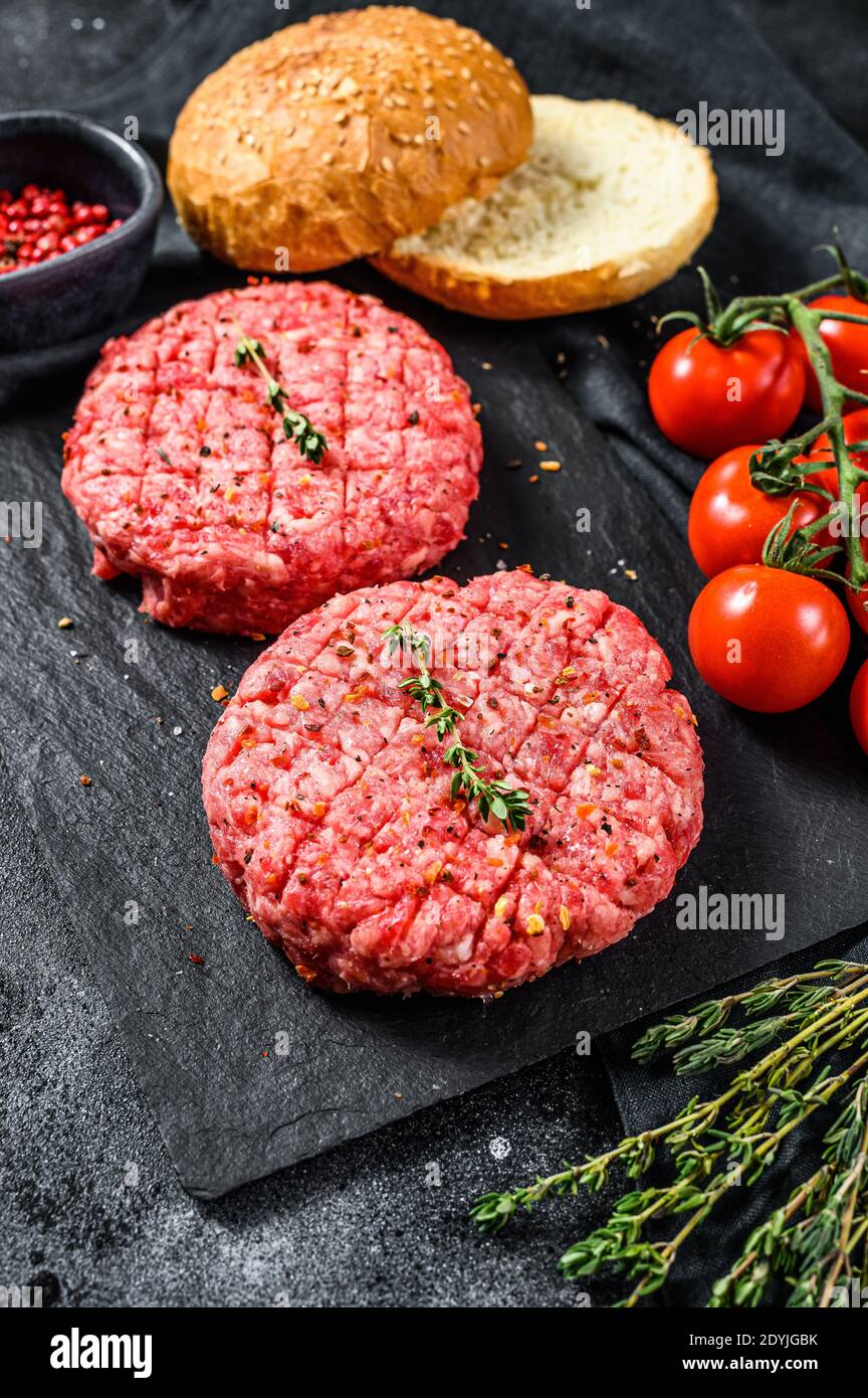 Ingredients for cooking burgers. Minced beef patties, buns, tomatoes, herbs and spices. Black