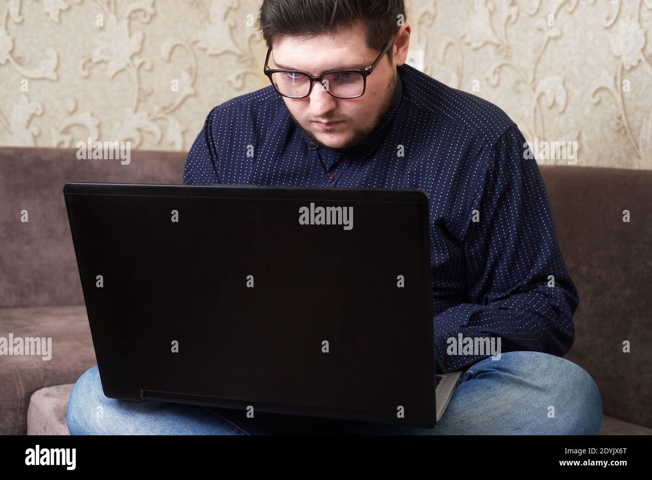 Caucasian male with glasses sitting at a laptop, copy space Stock Photo