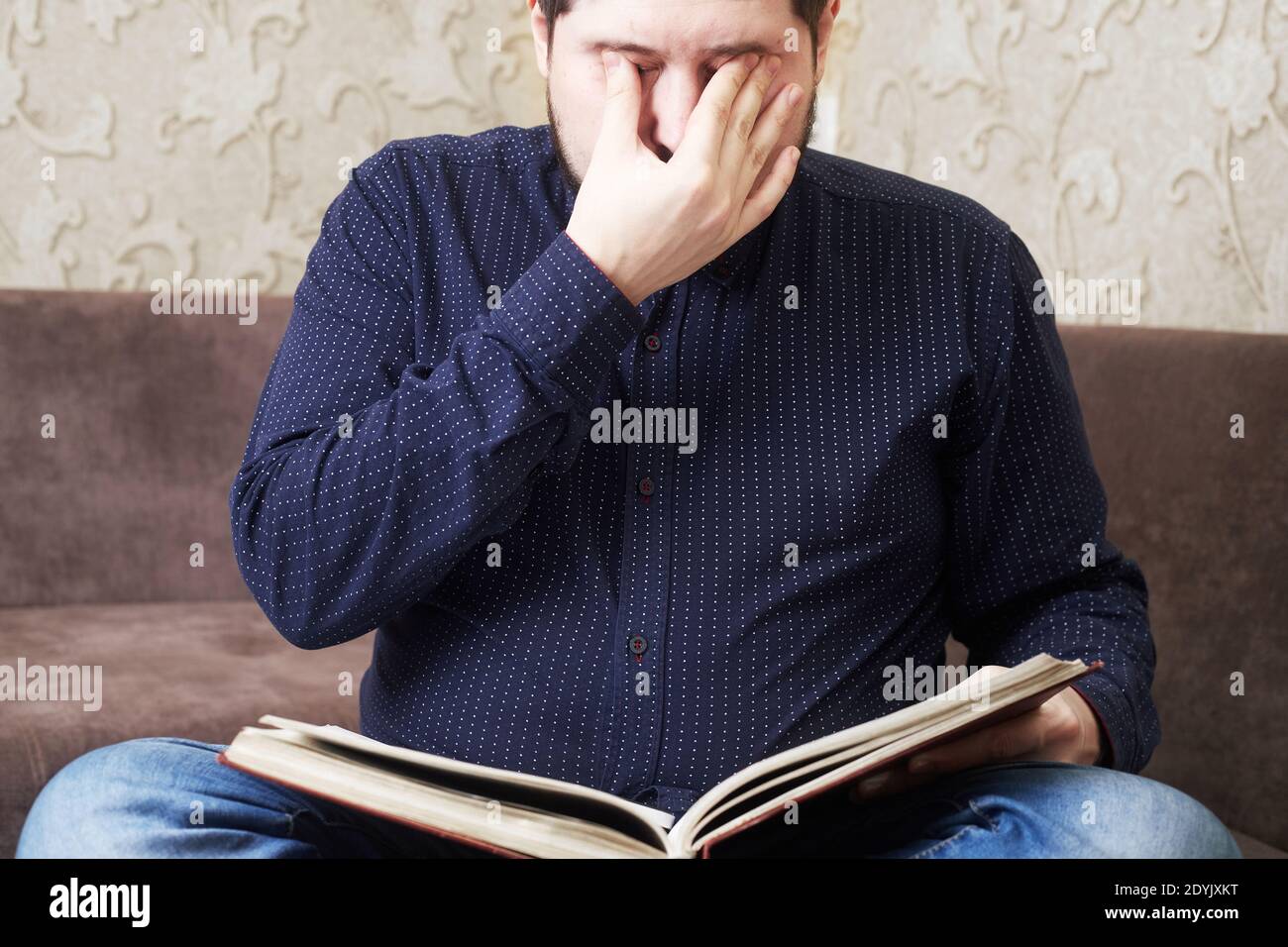 Concept, Caucasian man's eyes hurt while reading a book, copies of