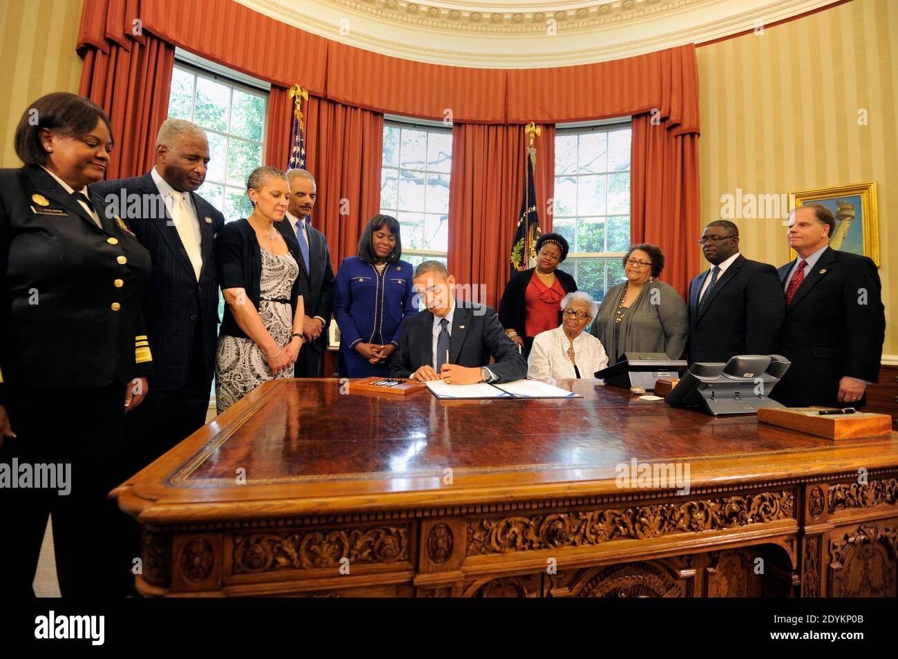 US President Barack Obama signs a bill in the Oval Office, May 24, 2013 in Washington, DC, USA, designating the Congressional Gold Medal commemorating the lives of the four young girls killed in the 16th Street Baptist Church Bombings of 1963 in Birmingham, Alabama. Witnessing (L-R) Surgeon General Regina Benjamin, Birmingham Mayor William Bell, Dr Sharon Malone Holder, Attorney General Eric Holder, Rep Terri Sewell (D-AL), Thelma Pippen McNair (mother of Denise McNair), Lisa McNair (sister of Denise McNair), Dianne Braddock (sister of Carole Robertson), Rev Arthur Price, Jr (pastor 16th Stree Stock Photo