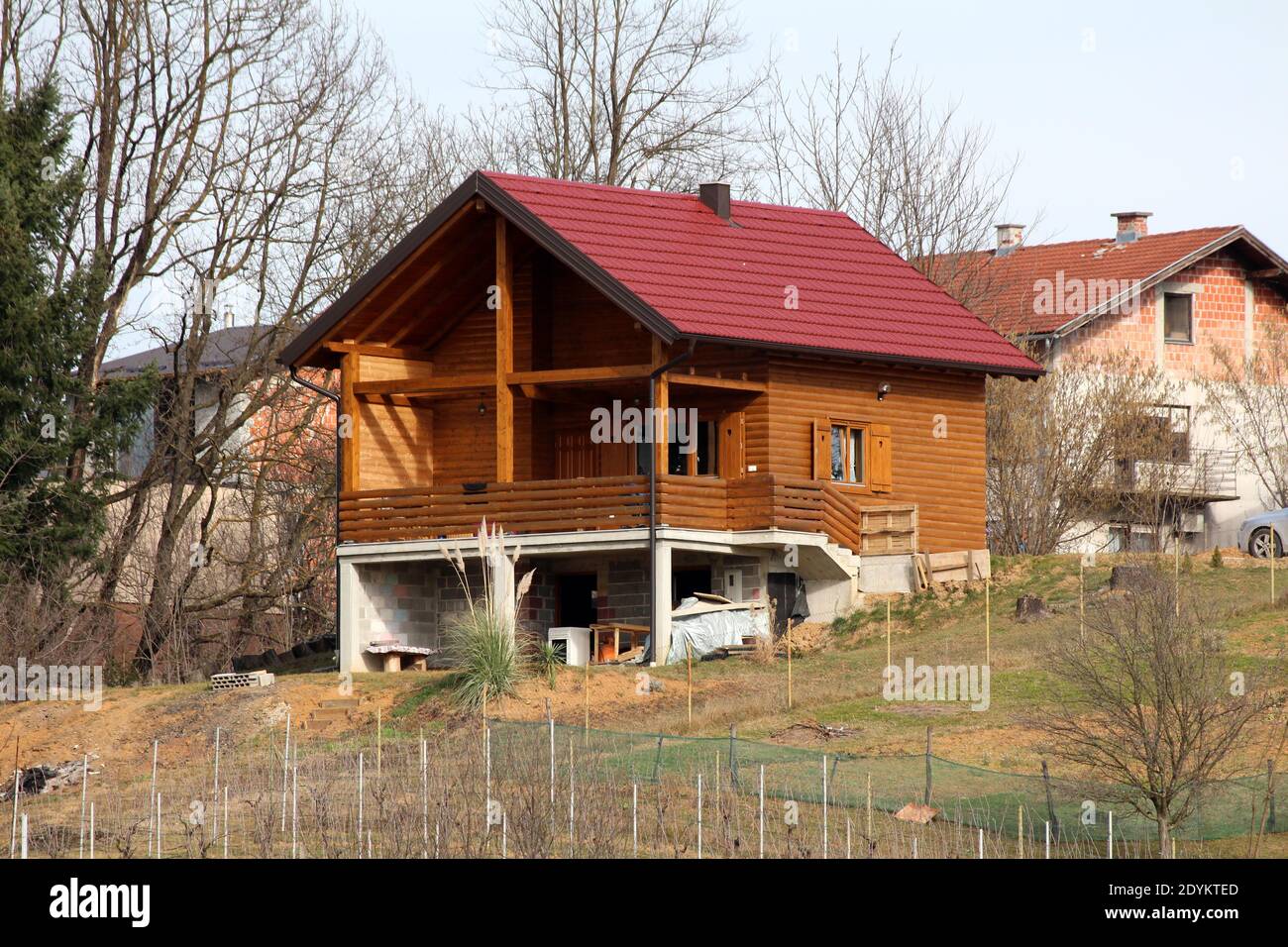 Modern Newly Built Wooden Log House With Big Open Porch In Front And New Roof Tiles On Side Of Small Hill Surrounded With Trees And Family Houses Stock Photo Alamy