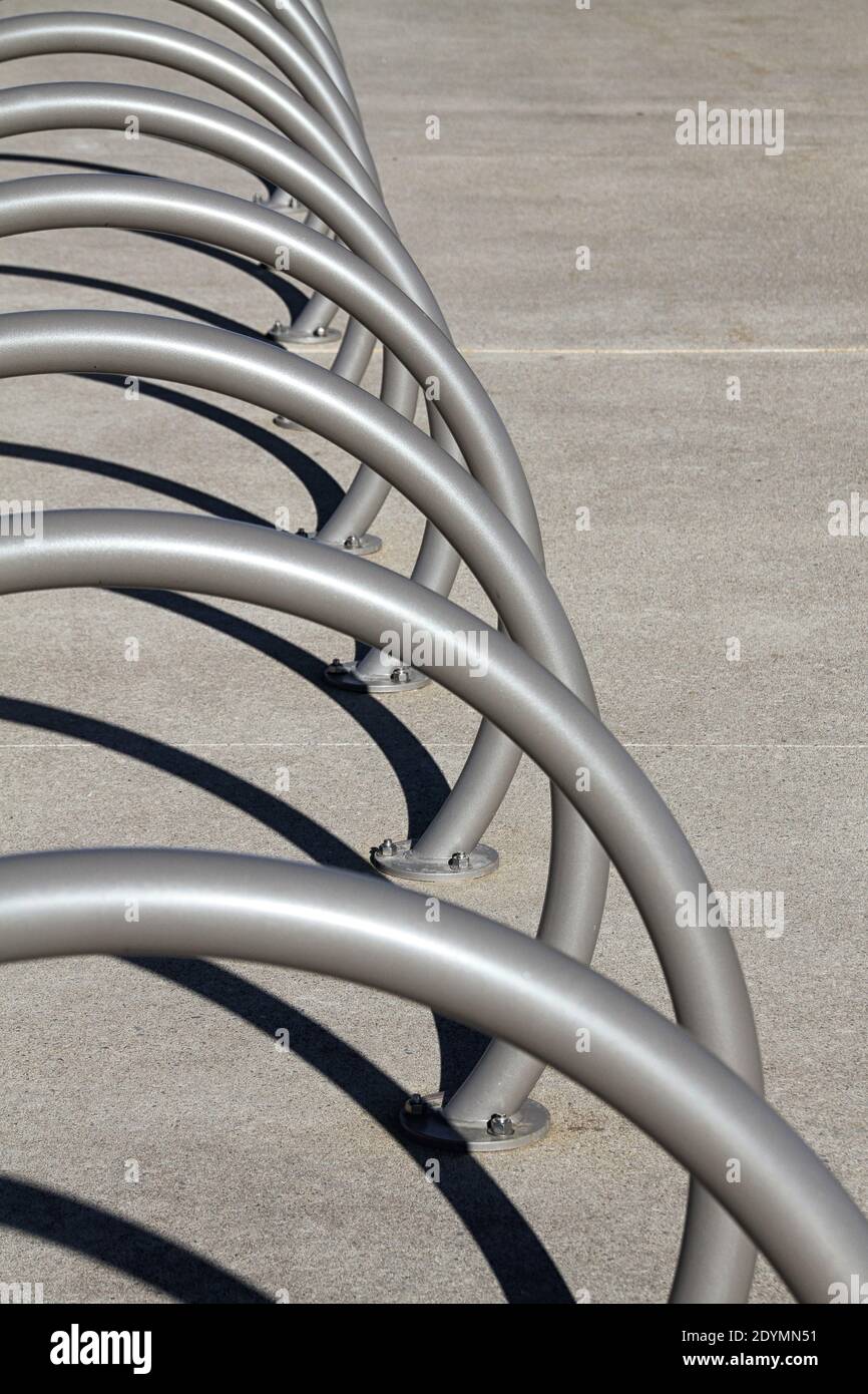 A row of empty round metal bike racks on a concrete sidewalk. Stock Photo