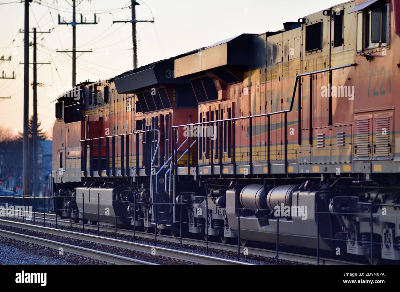 Bartlett, Illinois, USA. Two Burlington Northern Santa Fe locomotives head up a Canadian Pacific Railway freight train into the final light of day. Stock Photo