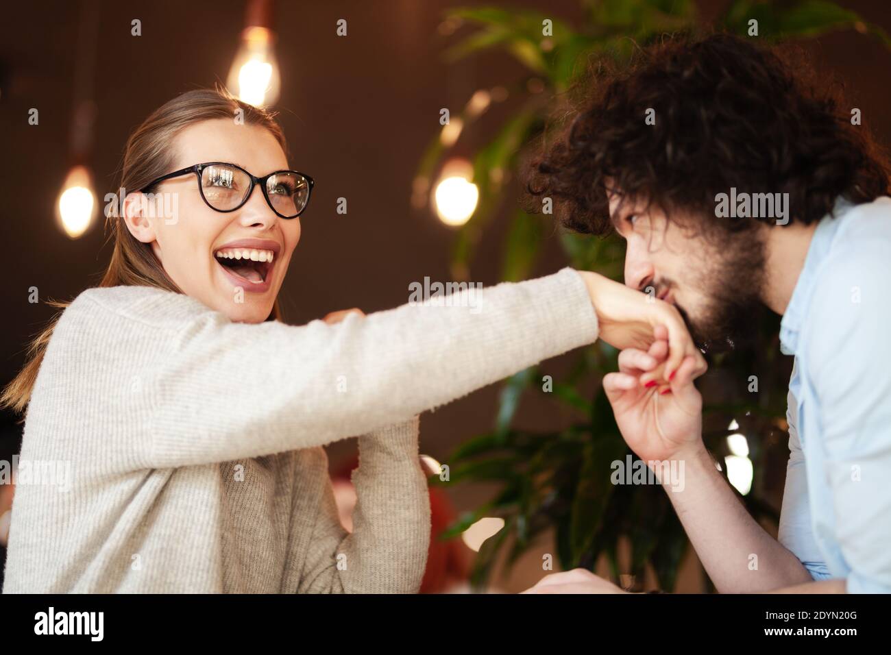 Lovely couple having a meeting at a cafe bar. Boy kissing girl's hand. Stock Photo