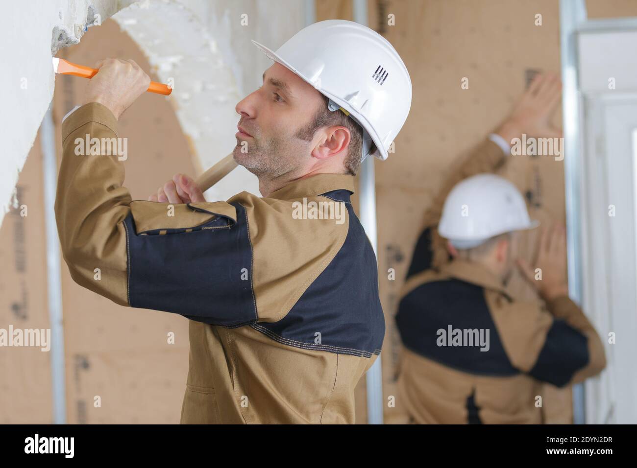 builders using a hammer to remove walls plaster Stock Photo Alamy