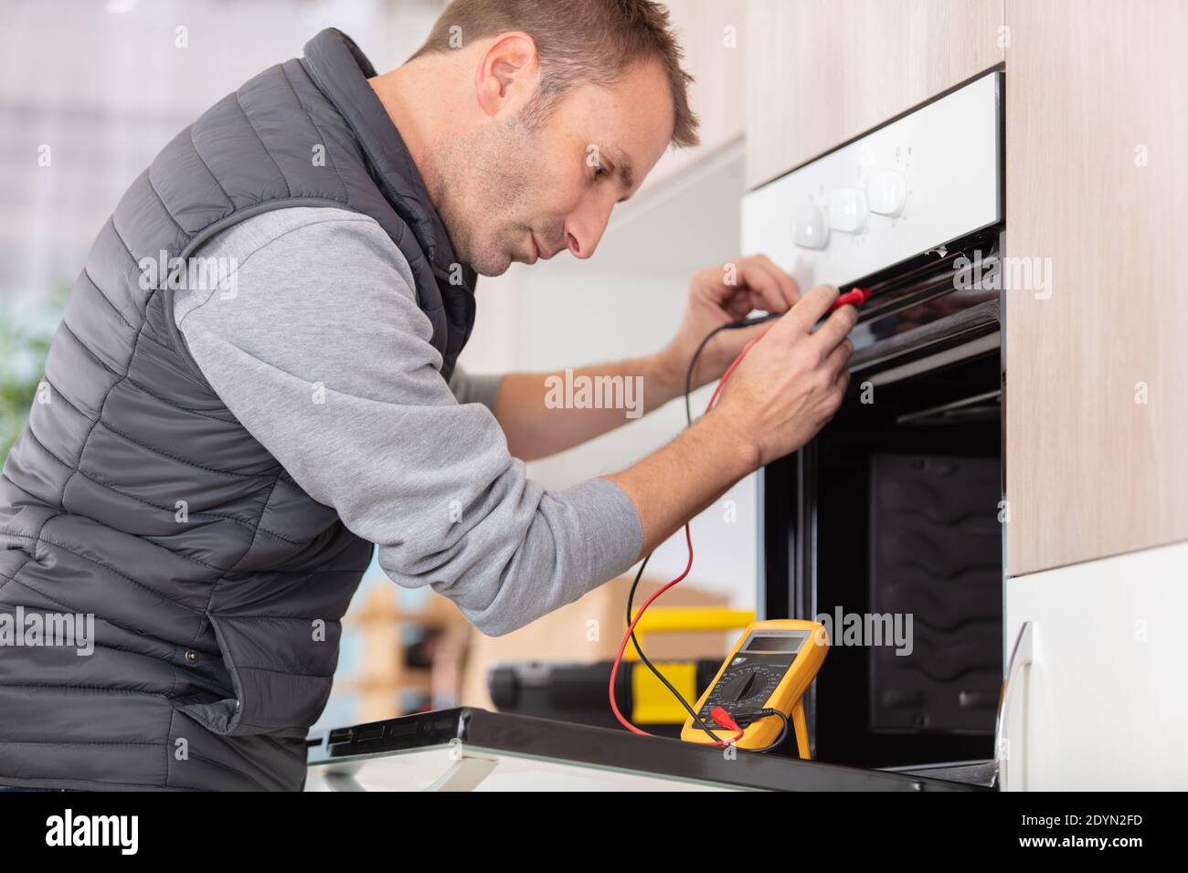 young male technician checking oven with digital multimeter Stock Photo