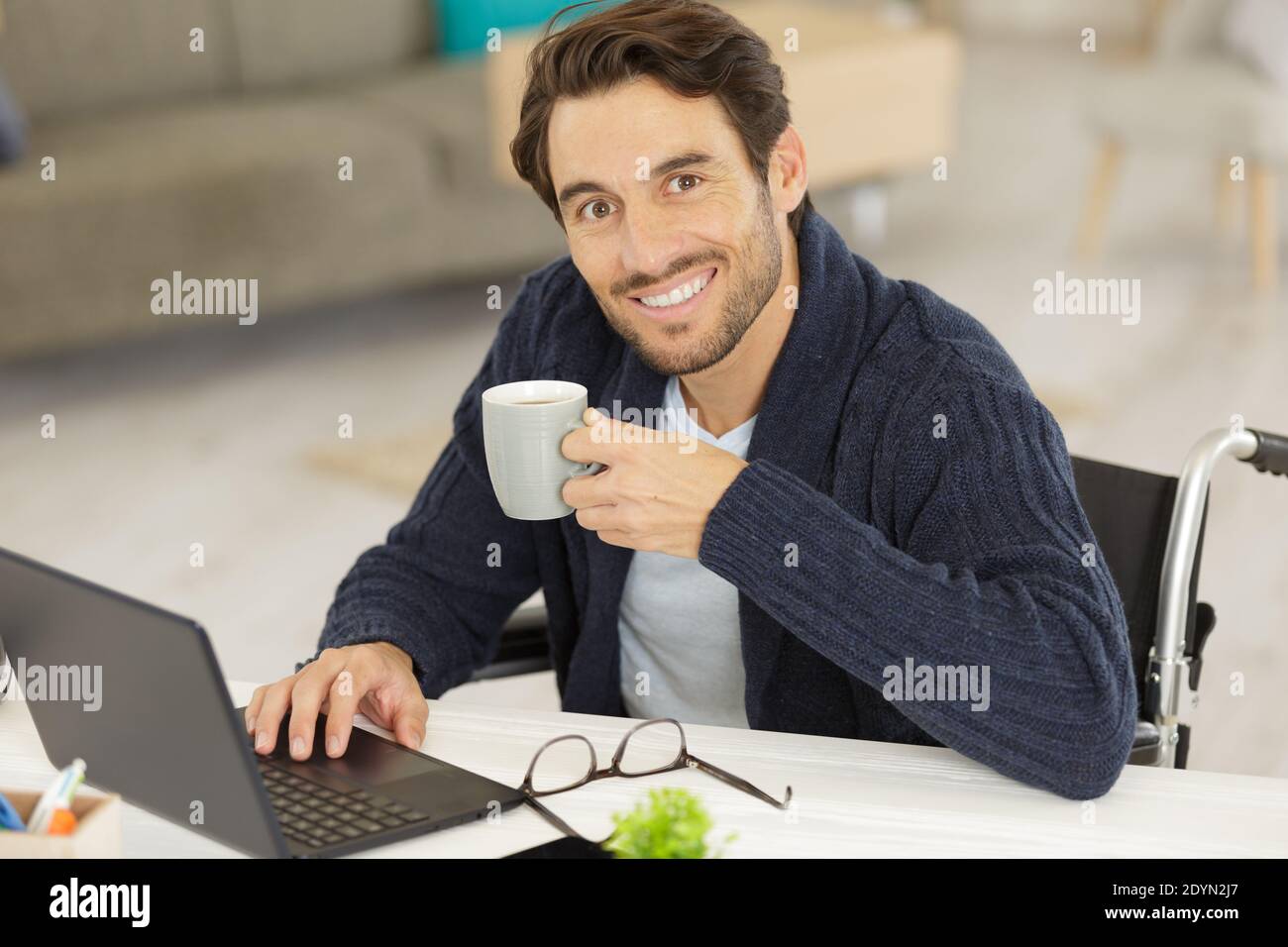 disabled young man using laptop and drinking coffee Stock Photo