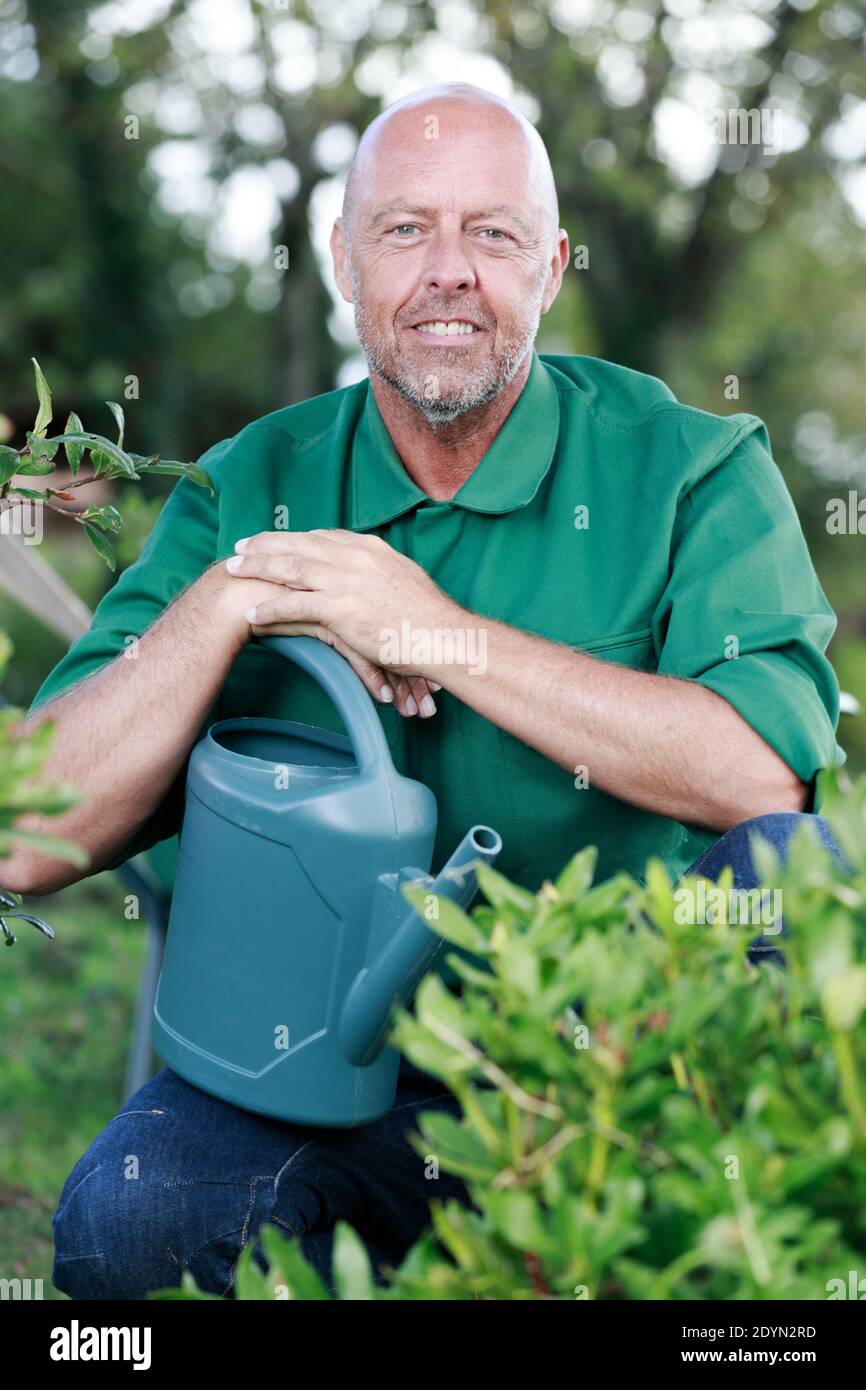 bold man smiling waters the plants Stock Photo - Alamy