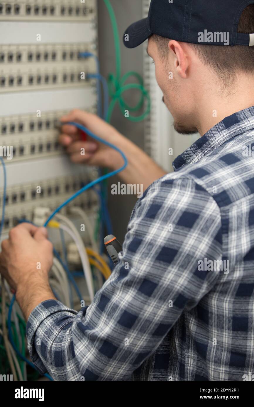 rear view of technician connecting cable in server Stock Photo