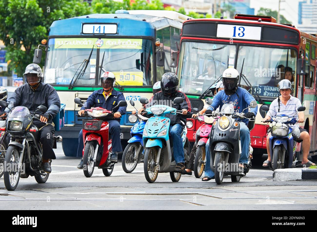 Colorful buses and motorcycles stopping at an intersection during rush hour near Lumpini Park in downtown Bangkok City, Asia Stock Photo