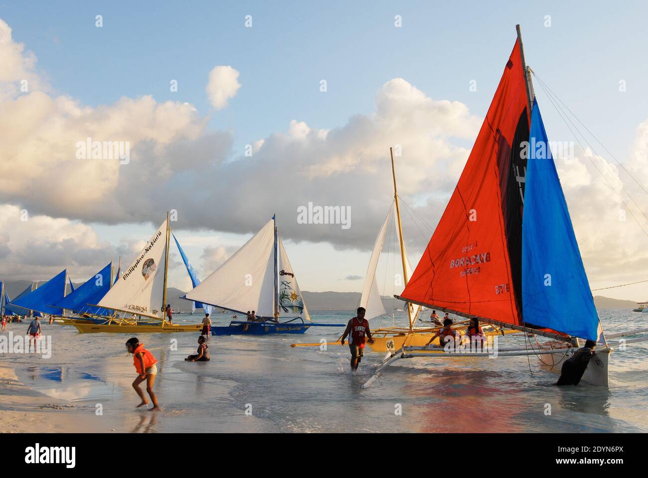 Colorful sailing boat along the White Beach on Boracay Island with few tourists and children present during sunset time, Philippines, Asia Stock Photo