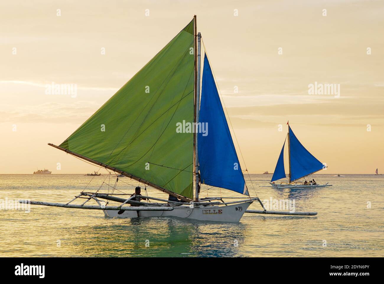 Colorful sailing boats against a golden sky along the White Beach on Boracay Island at sunset time, Philippines, Asia Stock Photo
