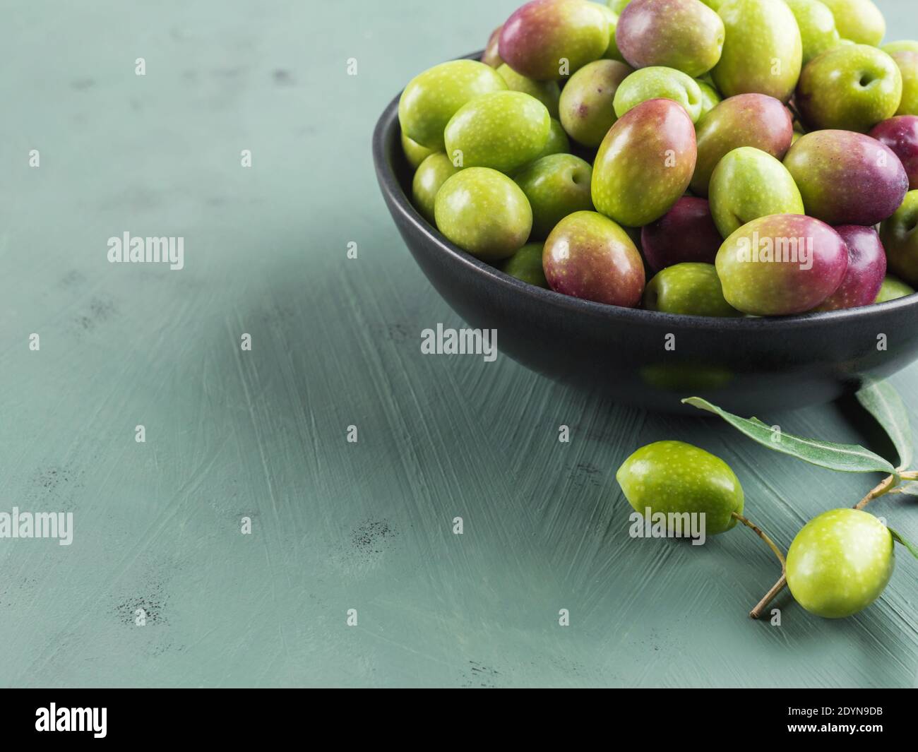 Freshly picked raw green olives in black bowl Stock Photo