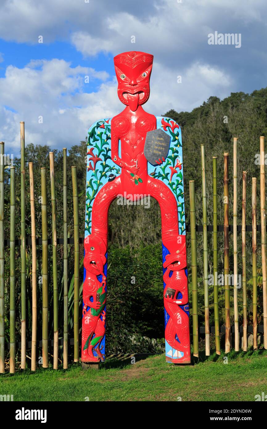A colorful wooden gateway with Maori carvings of human figures. Te Puna Quarry Park, New Zealand Stock Photo