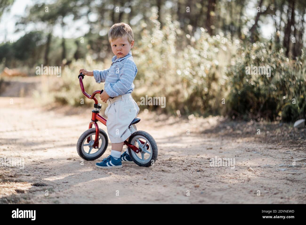 Cute toddler riding his balance bicycle on a dirt road Stock Photo