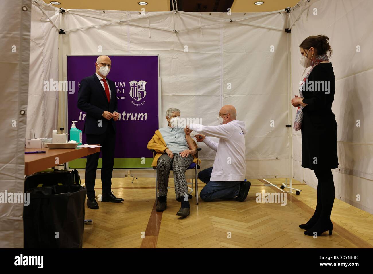 Hamburg, Germany. 27th Dec, 2020. Peter Tschentscher (l), First Mayor in Hamburg, Melanie Leonhard (r, both SPD), Senator for Labour, Social Affairs, Family and Integration in Hamburg, watch as Karin Sievers (84) receives the first vaccination from Dirk Heinrich (M r), Medical Director of the Vaccination Centre Hamburg at the Messehallen, at the Hospital zum Heiligen Geist in the Poppenbüttel district. On Sunday, the Corona vaccinations with the Covid-19 vaccine from Biontech-Pfizer started in Germany. Credit: Christian Charisius/dpa/Alamy Live News Stock Photo