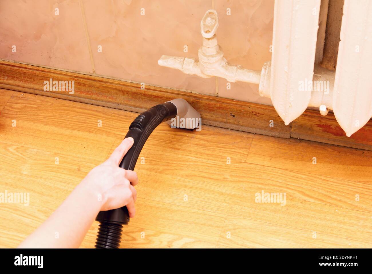 A woman is cleaning the baseboard with a vacuum cleaner Stock Photo Alamy