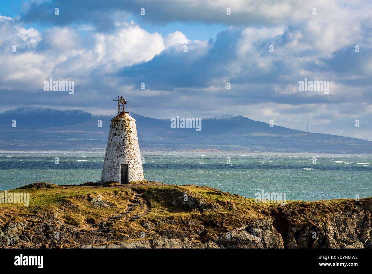 The original Twr Bach lighthouse on Llanddwyn island with snow covered Snowdonia National Park in the background, Anglesey Stock Photo