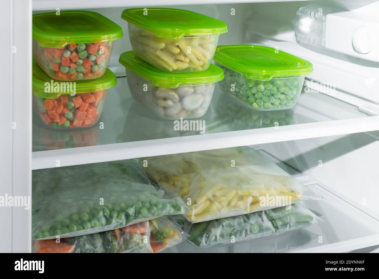 Plastic containers and bags with different frozen vegetables in