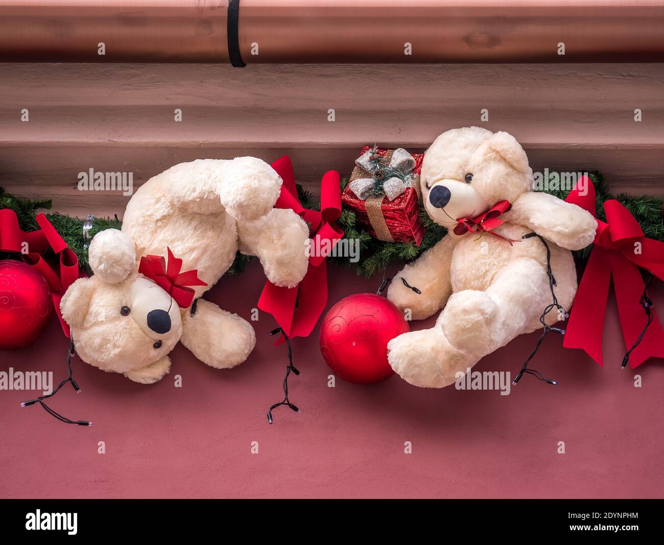 Holiday ornament with red globes and teddy bears on a building's wall