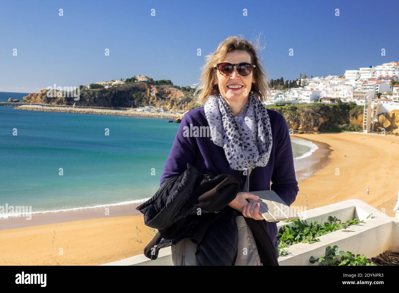 Middle Aged Caucasian Woman Poses For Photo At Albufeira Old Town Fishermans Beach In Albufiera The Algarve Portugal Winter Travel. Model Released Stock Photo