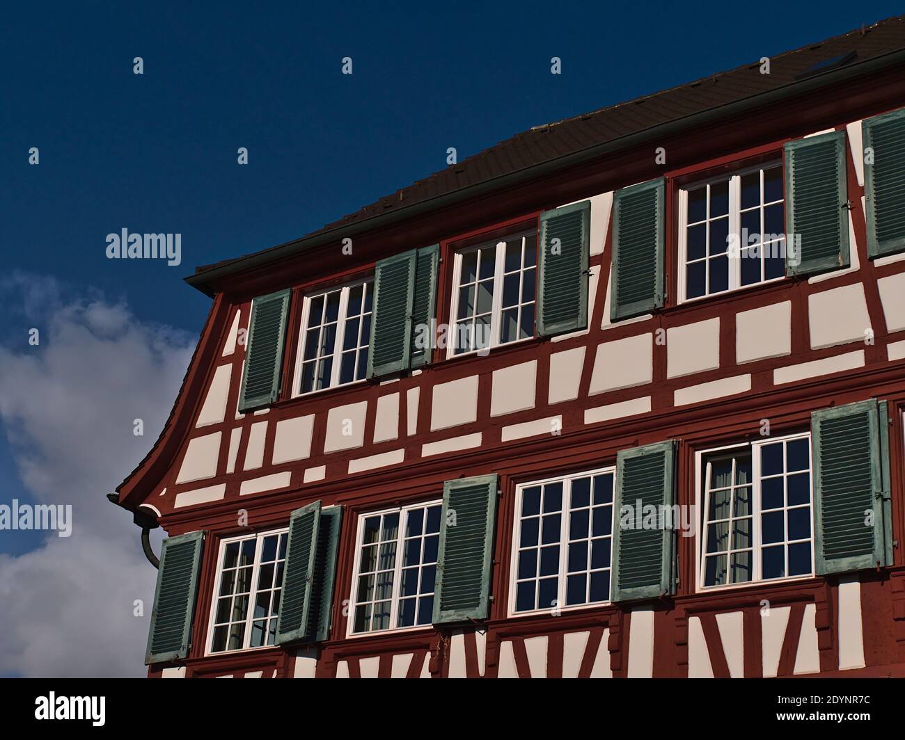 Closeup view of historic half-timbered house with beautiful white and red colored facade and and green painted window shutters in center of Hagnau. Stock Photo