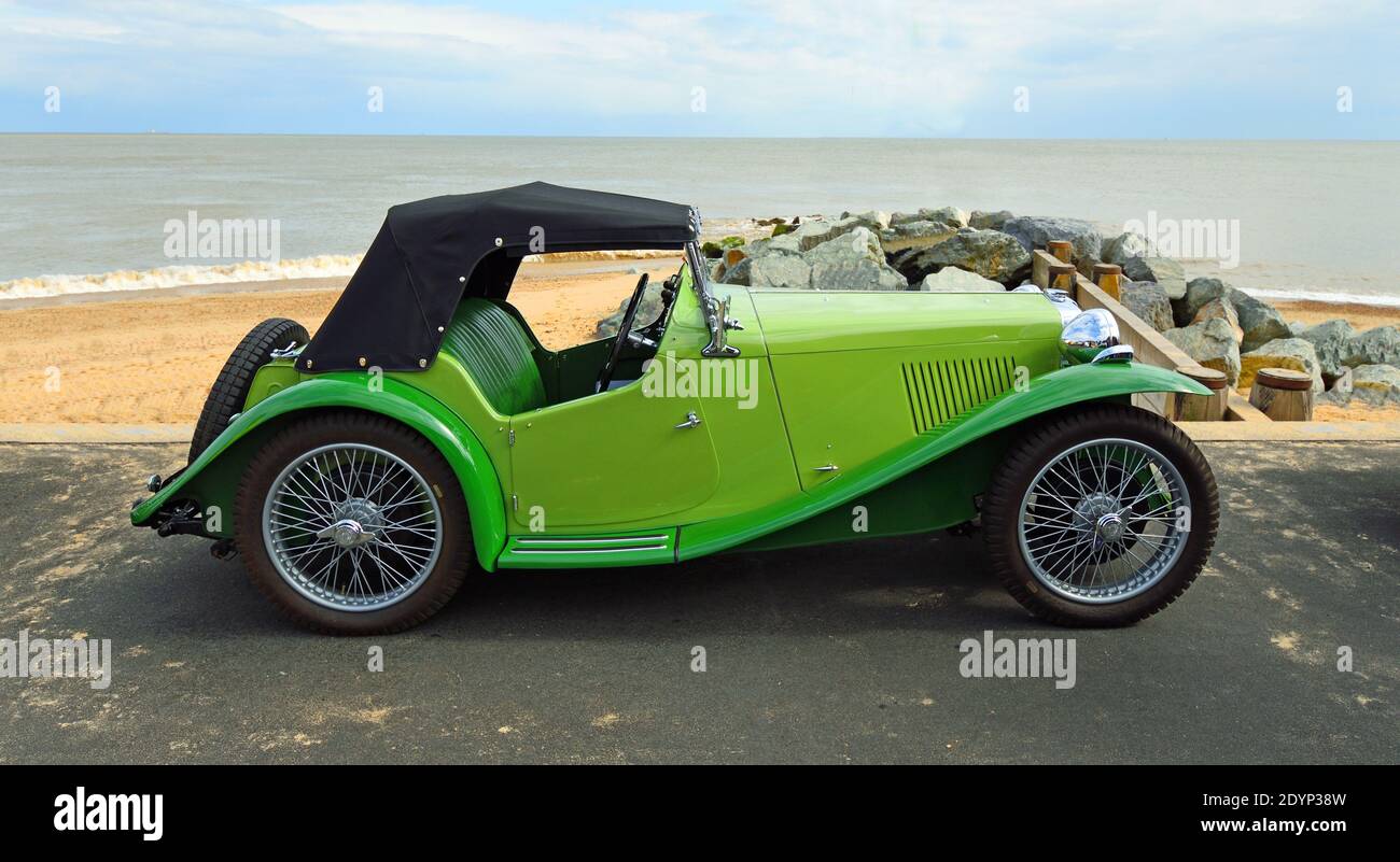 Classic  Green MG  Sports Car parked on seafront promenade with beach and sea in background. Stock Photo