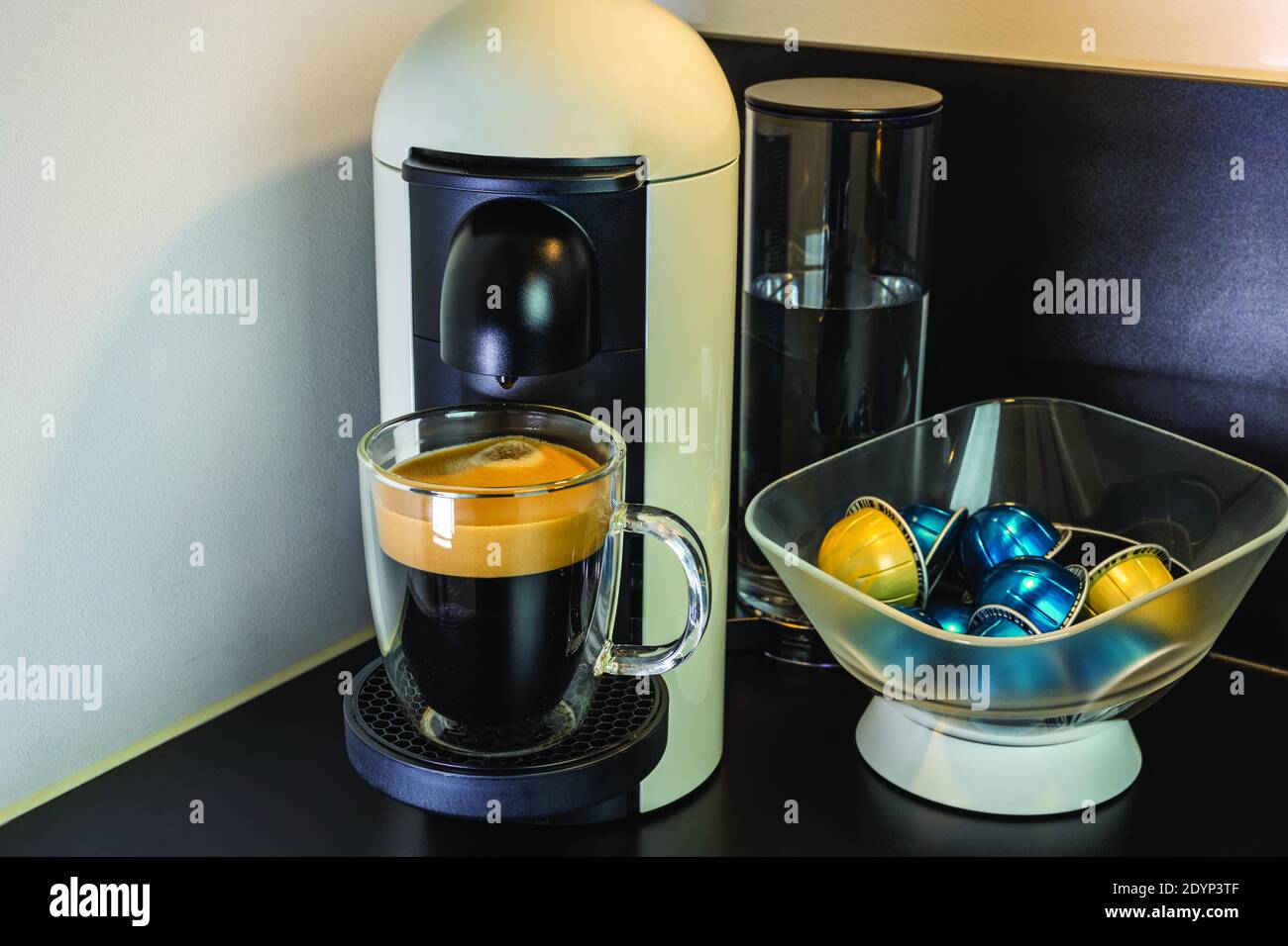 Close up view of coffee from capsule coffee machine into glass cup ...