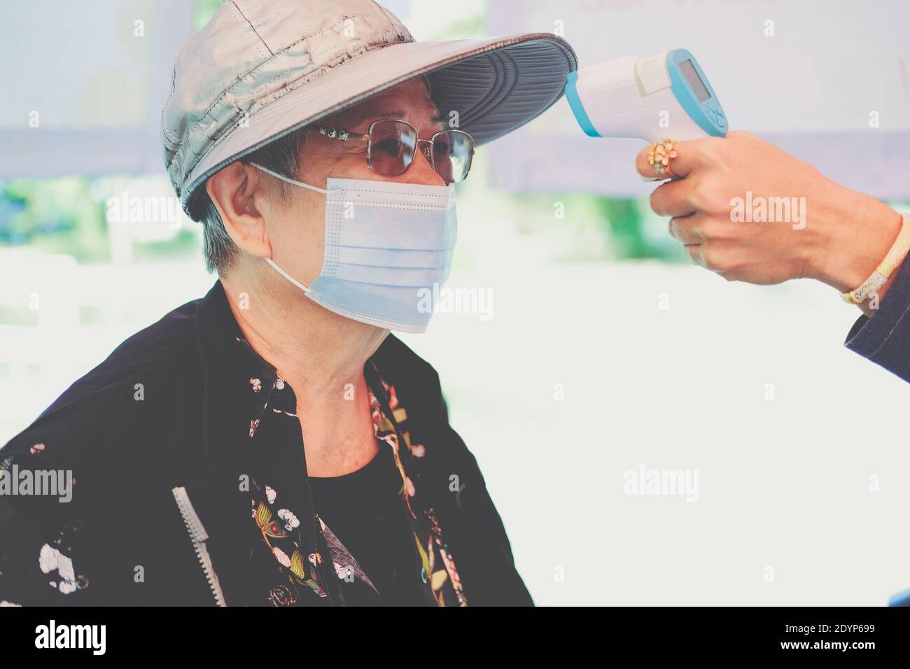 hand measuring body temperature of old woman with infrared forehead ...