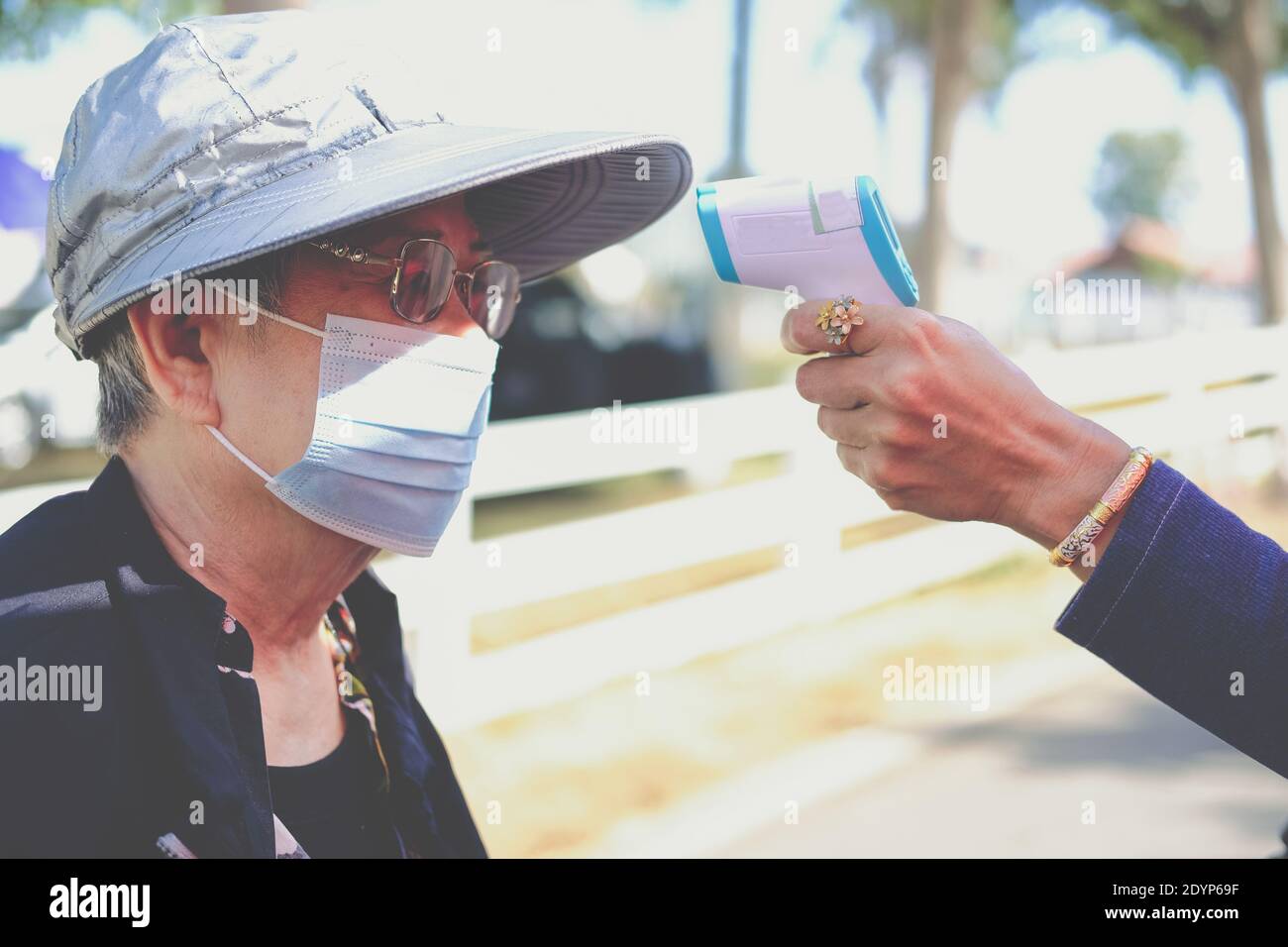 hand measuring body temperature of old woman with infrared forehead ...