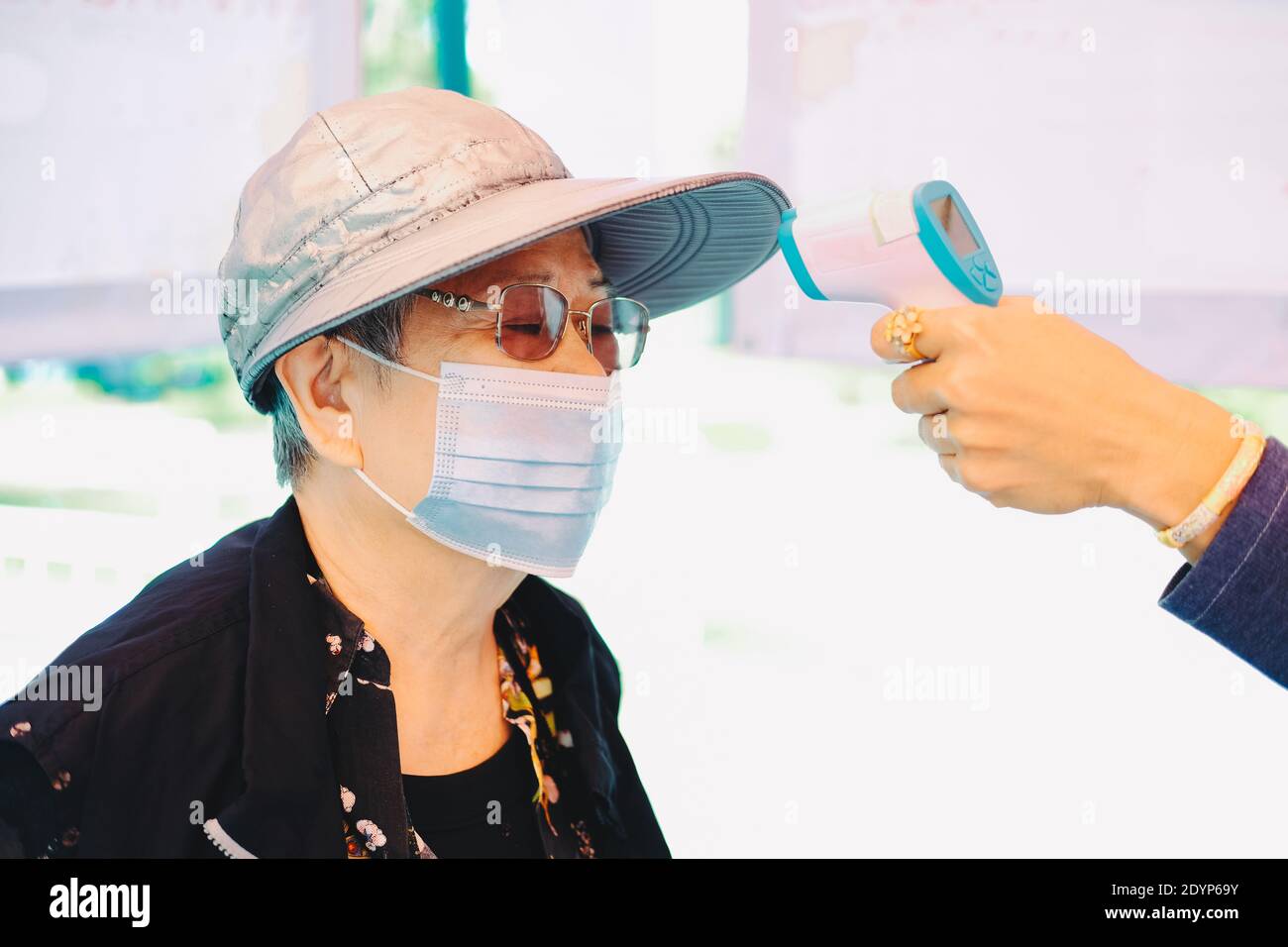 hand measuring body temperature of old woman with infrared forehead ...