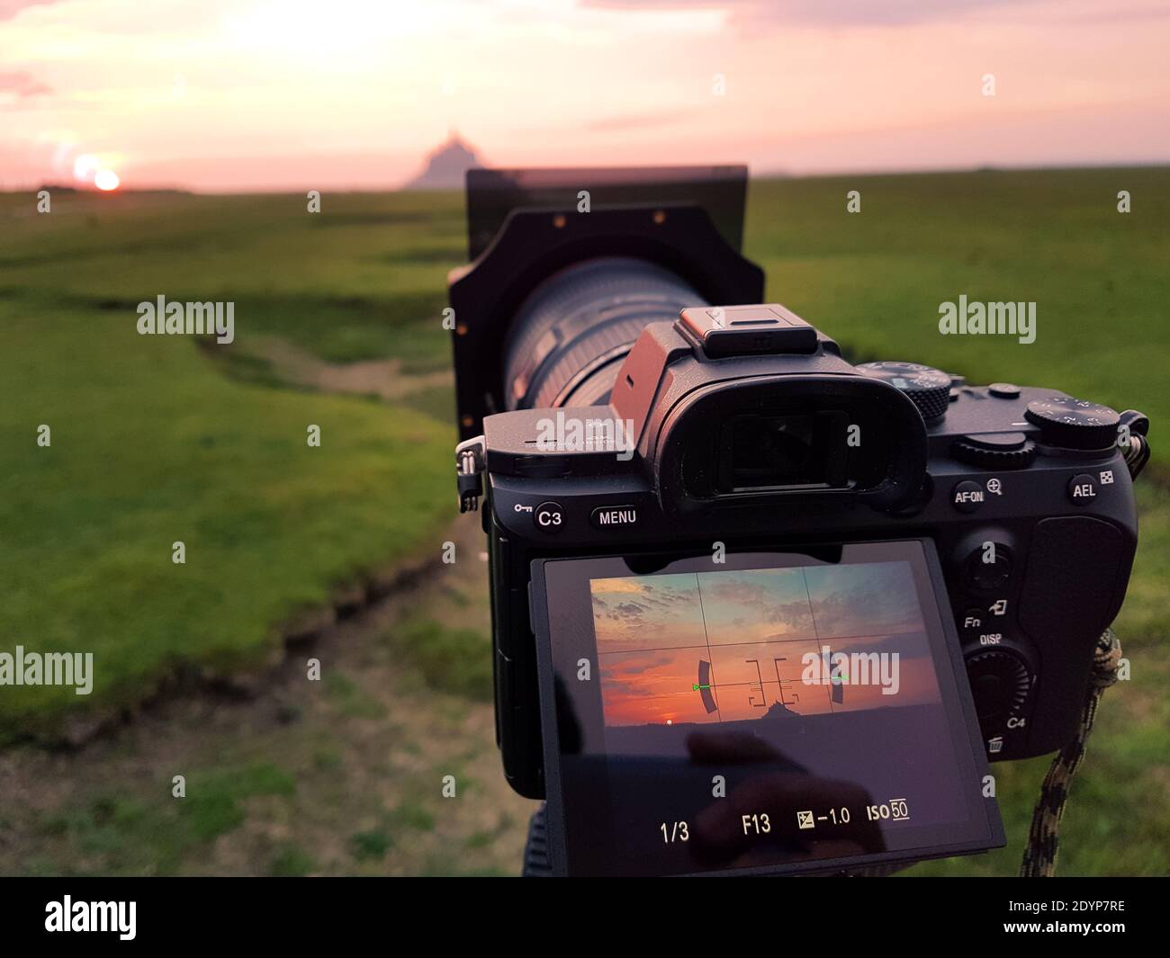 Camera on a tripid ready to take a photo of the Mont Saint Michel at  sunset. Nobody Stock Photo - Alamy