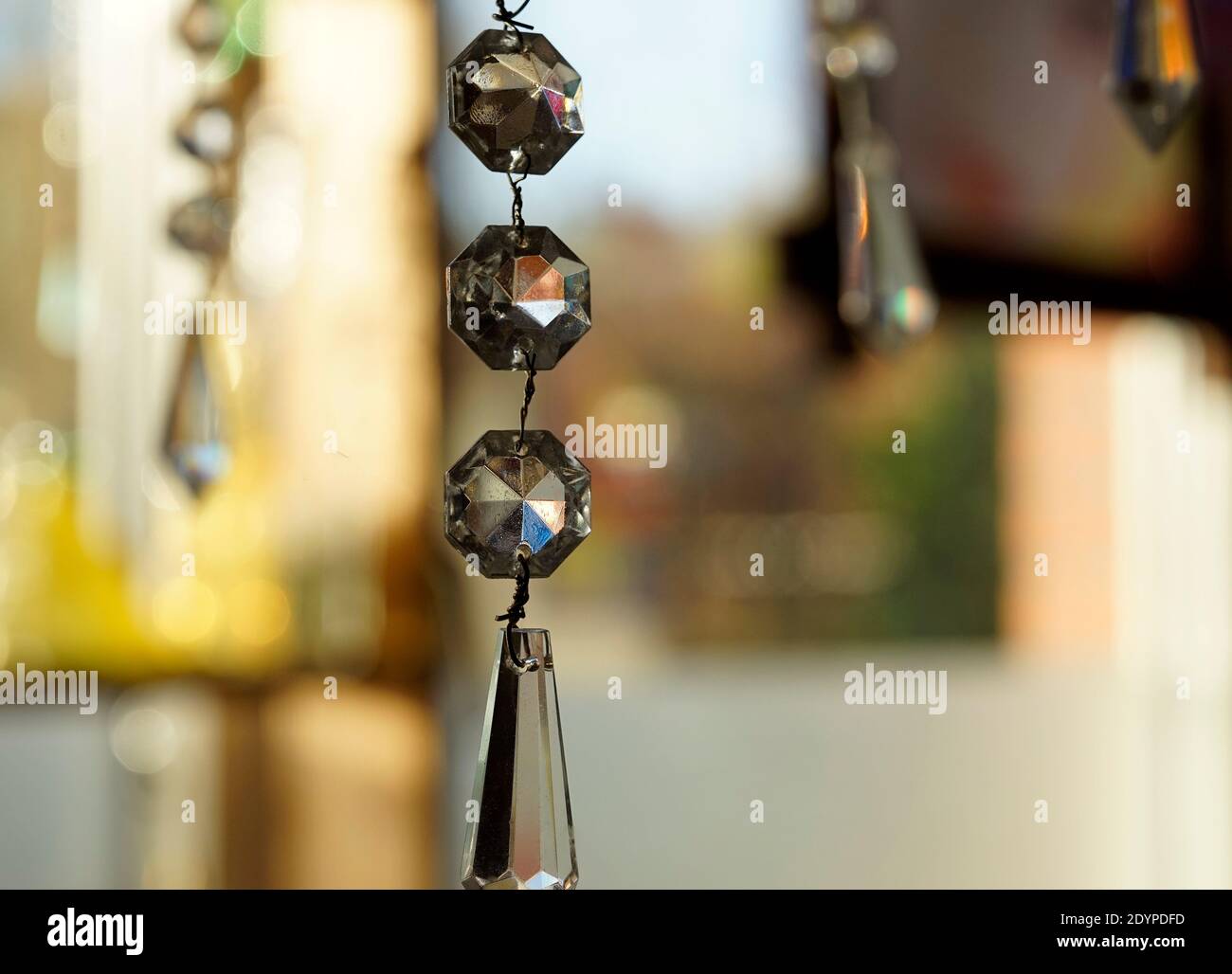 Chandelier crystals catching light. In the background  a colorful bokeh of different objects in the window. Feng Shui Stock Photo