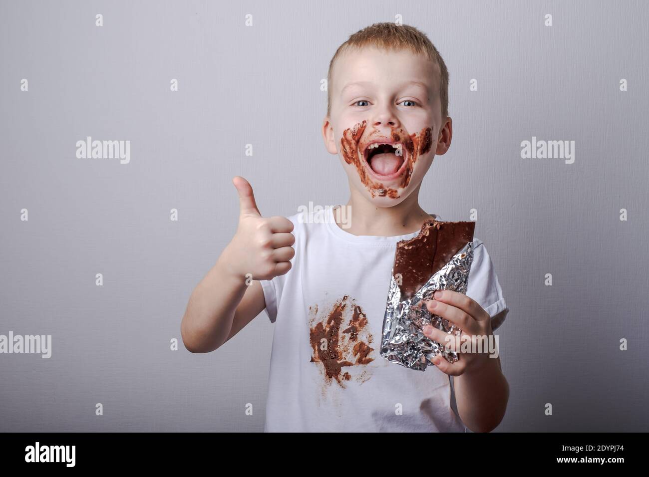 boy eating chocolate with a stain on clothes. Stains on a white ...
