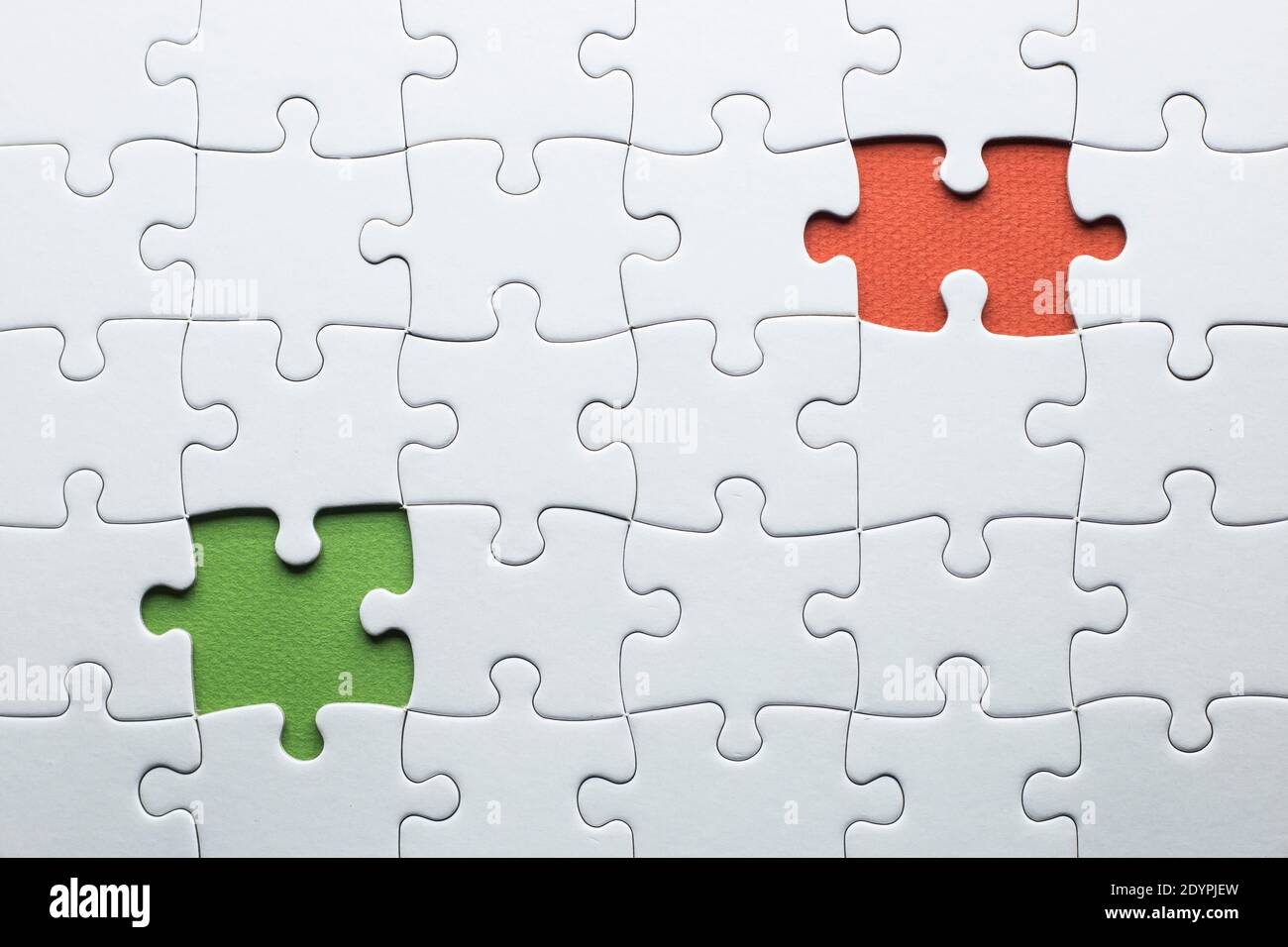 A puzzle is missing two pieces to be completed in different colors. white  pieces and one piece in green and one in orange to add text Stock Photo -  Alamy