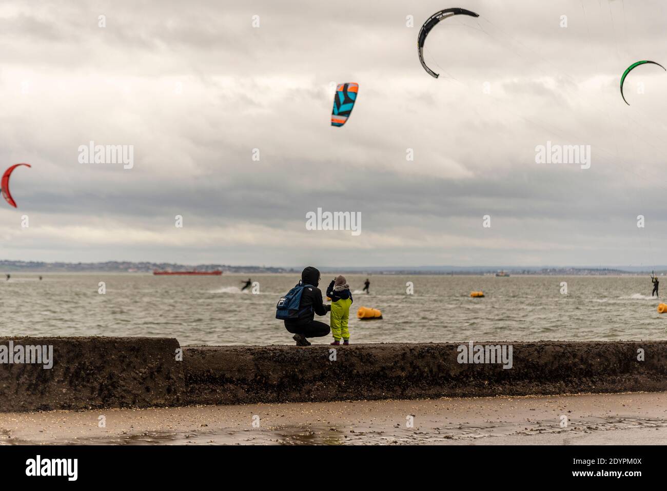 Adult and child watching Kitesurfing on Boxing Day in Southend on Sea, Essex, UK. Inspiring the young. Mother and child together Stock Photo