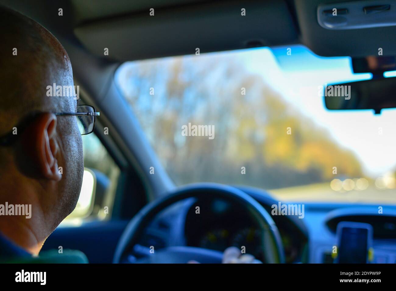 Elderly man with glasses driving a car while driving rear view Russia, Kursk region, Zheleznogorsk, October2016. Selective focus on the driver's glass Stock Photo